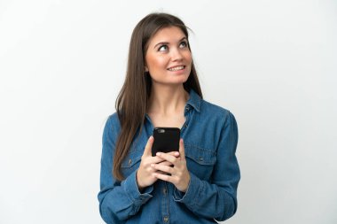 Beyaz arka planda izole genç beyaz kadın cep telefonu kullanarak ve yukarı bakarak