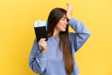 Sarı arka planda izole edilmiş pasaport taşıyan genç beyaz kadın bir şey fark etti ve çözüme niyetlendi.