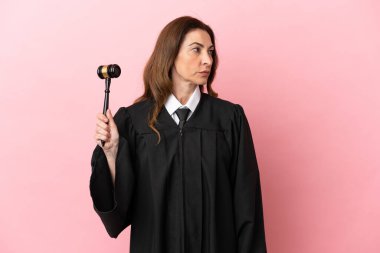 Pembe arka planda izole edilmiş orta yaşlı yargıç kadın.