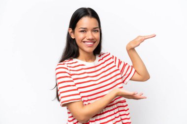 Beyaz arka planda izole edilmiş genç Kolombiyalı kadın ilan vermek için kopyalama alanı tutuyor.