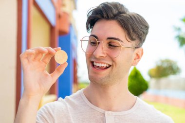 Elinde Bitcoin tutan yakışıklı bir genç.