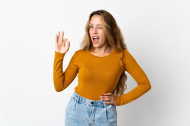 Mavi arka planda izole edilmiş genç sarışın kadın parmaklarıyla işaret veriyor.