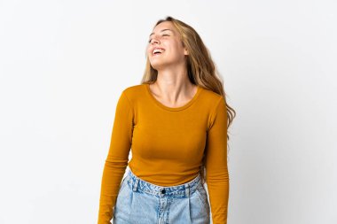 Genç sarışın kadın mavi arka planda yalnız gülüyor.