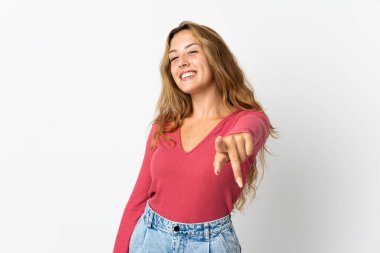 Mavi arka planda izole edilmiş genç sarışın kadın mutlu bir ifadeyle öne bakıyor.