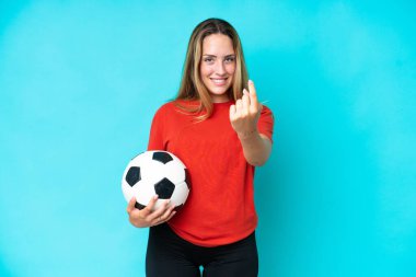 Genç futbolcu kadın mavi arka planda izole edilmiş bir şekilde geliyor.