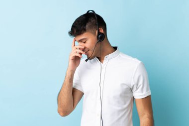 Kolombiyalı tele-pazarlamacı, kulaklıkla çalışıyor, gülerek.