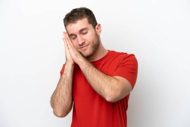 Beyaz arka planda izole edilmiş genç beyaz bir adam uyku jesti yapıyor.