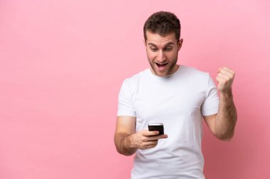 Pembe arka planda izole genç beyaz adam şaşırdı ve bir mesaj gönderiyor.