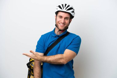 Beyaz arka planda izole edilmiş termal sırt çantalı beyaz bir adam gülümserken bir fikir sunuyor.