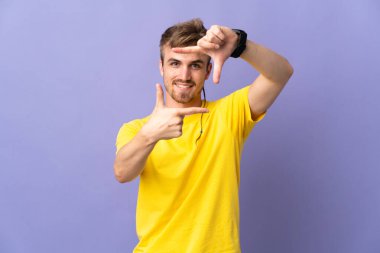 Genç yakışıklı sarışın adam, mor arka planda izole edilmiş, odaklanmış yüz. Çerçeve sembolü