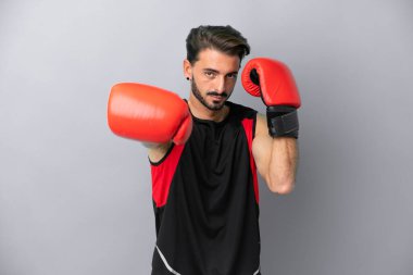 Gri arka planda boks eldivenli, beyaz, genç bir adam.