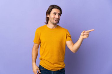 Mor arka planda izole edilmiş genç yakışıklı bir adam parmağını kaldırarak çözümü anlamaya çalışıyor.