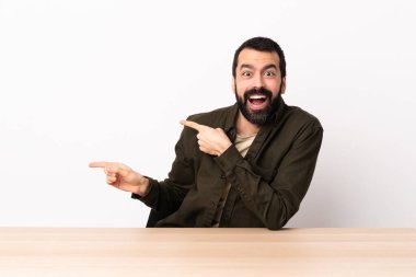 Masada sakallı beyaz adam şaşırmış ve işaret ediyor..