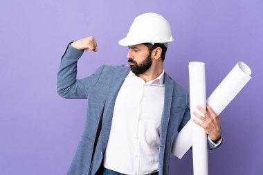 Miğferli genç bir mimar, elinde yalıtılmış mor arka plan planları var.