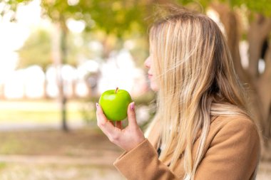 Arka tarafta elmalı güzel sarışın bir kadın var.