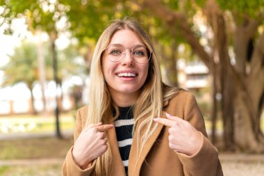 Genç, güzel, sarışın bir kadın. Yüzünde sürpriz bir ifade var.