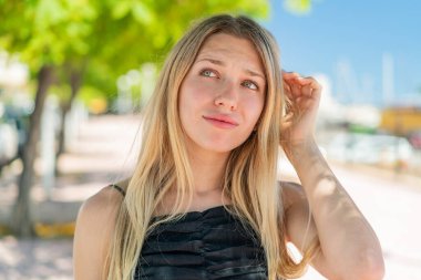 Açık havada kuşkuları olan genç sarışın bir kadın.