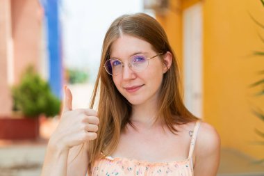 Açık havada genç bir Fransız kız Gözlüklü ve başparmağıyla