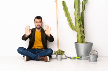 Bahçıvan içeride yerde oturuyor. Durma hareketi yapıyor ve hayal kırıklığına uğruyor.