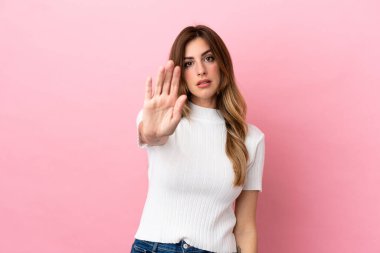 Pembe arka planda izole edilmiş beyaz kadın dur hareketi yapıyor.