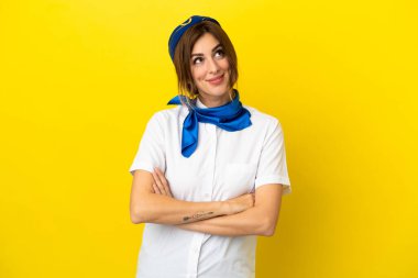 Uçak hostesi kadın sarı arka planda izole edilmiş gülümserken yukarı bakıyor.