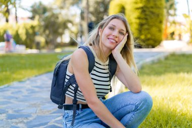 Açık havada genç sarışın bir kadın Neşeli bir ifadeyle