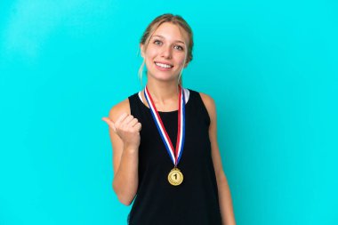 Mavi arka planda madalyaları olan beyaz bir kadın bir ürünü sunmak için yan tarafa bakıyor.