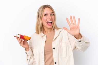 Beyaz arka planda saşimi tutan beyaz kadın parmaklarıyla beşi sayıyor.