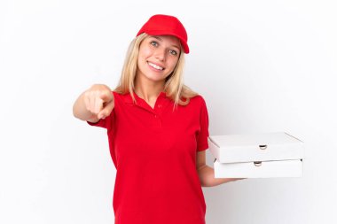 Beyaz arka planda pizza taşıyan teslimatçı kadın mutlu bir ifadeyle öne bakıyor.