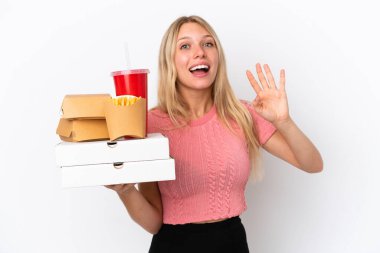 Beyaz bir kadın, elinde yağlı yiyeceklerle mavi arka planda izole edilmiş, mutlu bir ifadeyle selamlıyor.