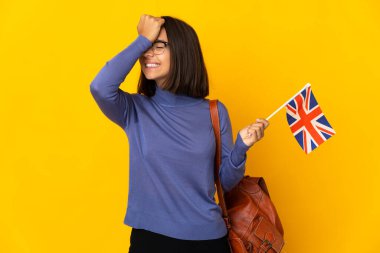 Sarı arka planda izole edilmiş Birleşik Krallık bayrağını tutan genç Latin kadın bir şey fark etti ve çözüme niyetlendi.