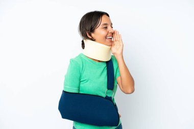 Boynunda boyunluk ve askısı olan genç İspanyol kadın beyaz arka planda izole edilmiş ve ağzı sonuna kadar açık bağırıyor.