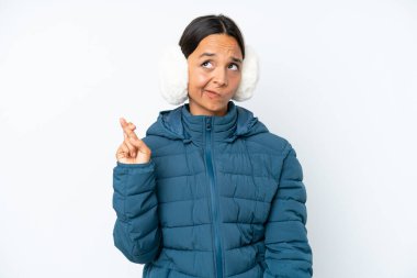 Kış kulaklığı takan genç İspanyol kadın beyaz arka planda izole edilmiş ve şans diliyor.