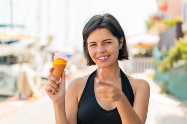 Açık havada kornet dondurması olan genç ve güzel Bulgar kadın kendinden emin bir ifadeyle seni işaret ediyor.