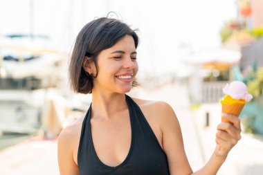 Açık havada kornet dondurması olan genç, güzel bir Bulgar kadın, neşeli bir ifadeyle.