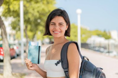 Genç, güzel Bulgar kadın elinde pasaport tutarken gülümsüyor.