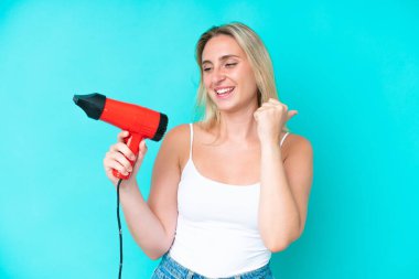 Mavi arka planda saç kurutma makinesi tutan beyaz bir kadın zaferi kutluyor.
