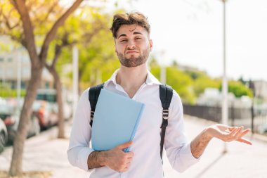 Dışarıdaki yakışıklı öğrenci omuzlarını kaldırırken şüpheyle hareket ediyor.