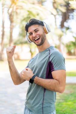 Açık havada kulaklıkla müzik dinleyen bir adam.