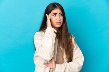 Kafkasyalı genç bir kadın mavi arka planda izole edilmiş, baş ağrısı var.