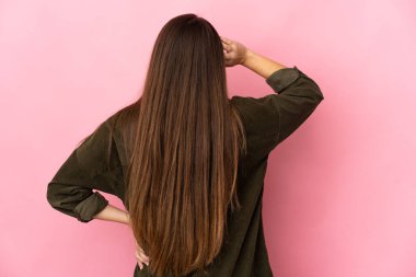 Genç beyaz kadın pembe arka planda izole edilmiş ve düşünüyor.