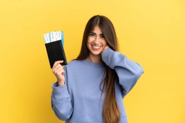 Sarı arka planda izole edilmiş pasaportu olan beyaz bir kadın gülüyor.