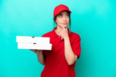 İş üniformalı bir pizzacı kadın mavi arka planda izole edilmiş pizza kutularını alıyor.