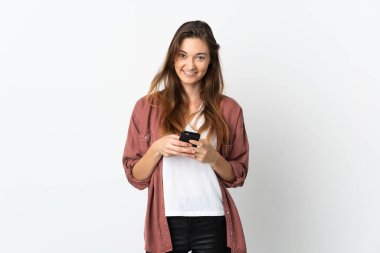 Beyaz arka planda izole edilmiş genç İrlandalı kadın cep telefonuyla mesaj gönderiyor.