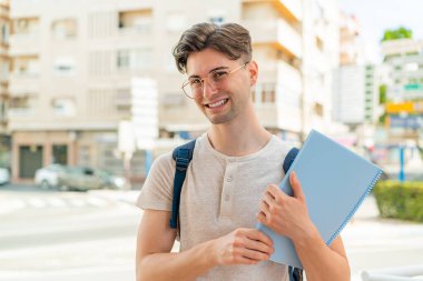 Açık havada gülümseyen yakışıklı bir öğrenci.