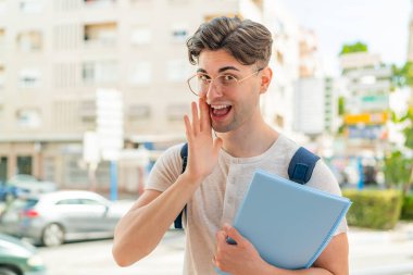 Genç yakışıklı bir öğrenci dışarıda bir şeyler fısıldıyor.