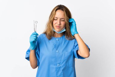 Beyaz arka planda izole edilmiş aletleri tutan kadın diş hekimi hayal kırıklığına uğramış ve kulaklarını kapatmış