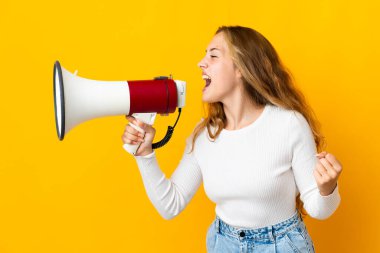 Sarı arka planda izole edilmiş genç sarışın bir kadın megafondan bir şey duyurmak için bağırıyor.