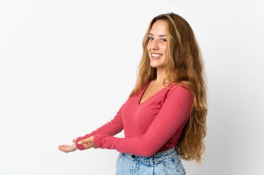 Mavi arka planda izole edilmiş genç sarışın kadın davet etmek için ellerini yana uzatıyor.