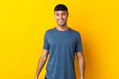 Kolombiyalı genç adam, sarı arka planda izole edilmiş, şaşırmış bir yüz ifadesi var.